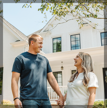 happy couple holding hands outside home