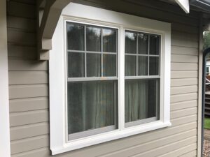Black vinyl double-hung window replacement on white residential siding in Magnolia